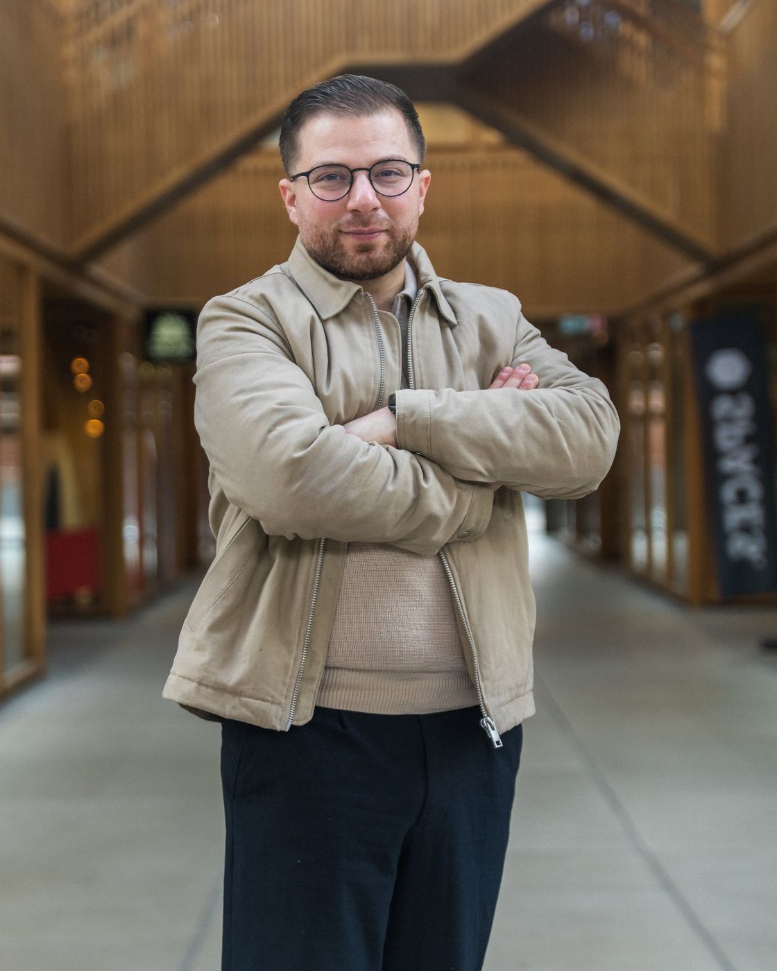 Portrait photo d’un homme, bras croisés, dans une galerie couverte